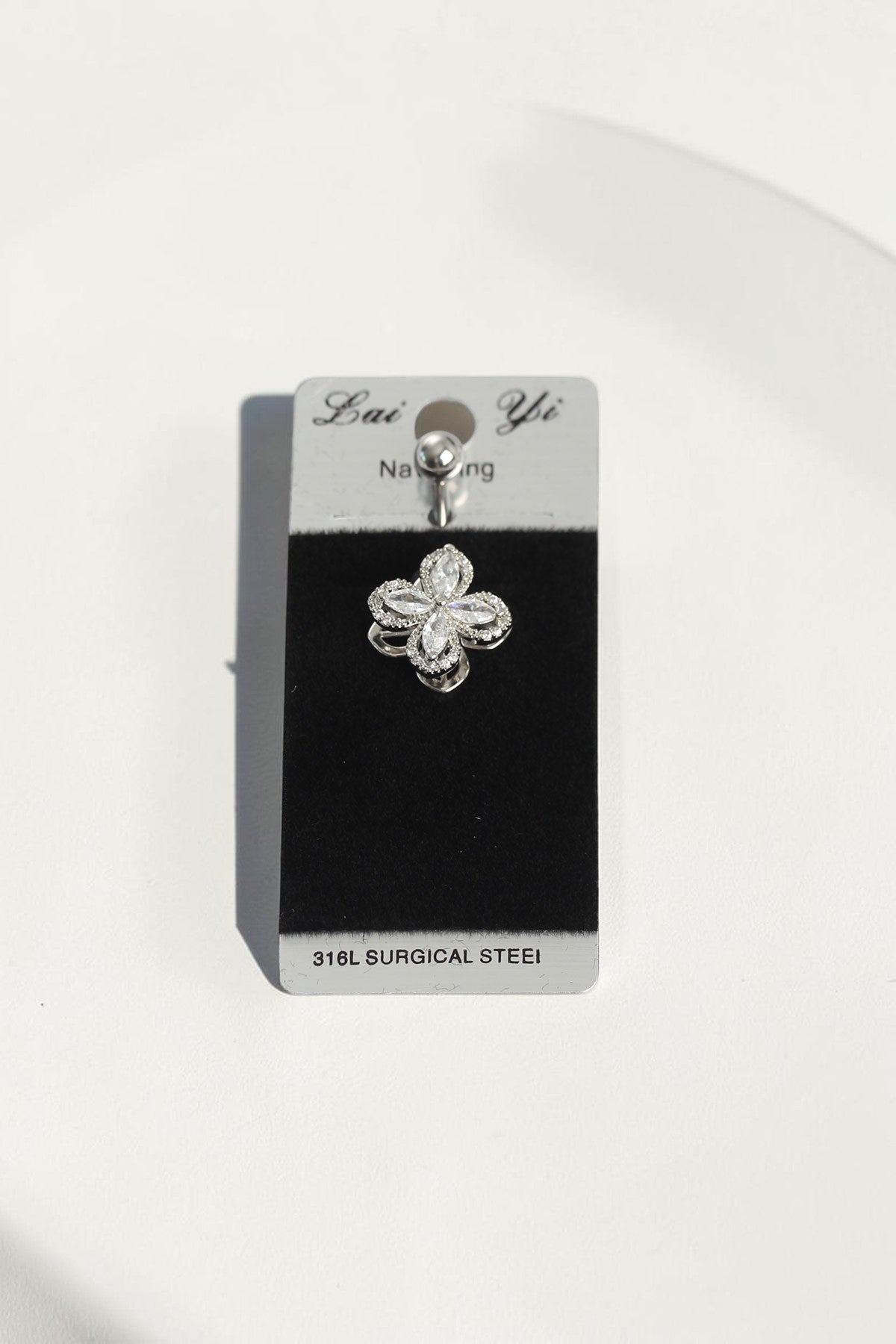 VORA HOUSE surgical steel belly button piercing with a rotating clover design featuring sparkling zircon stones.